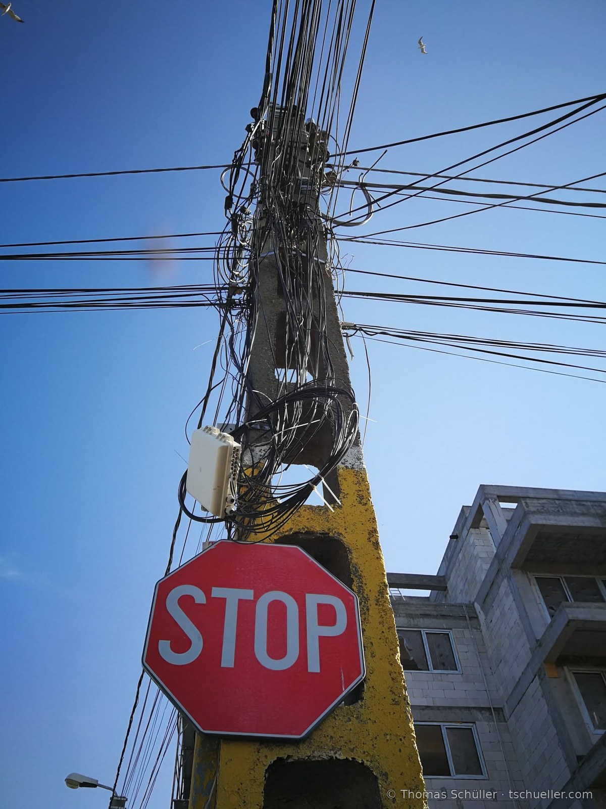 Betonmast mit Kabelbündeln und Stoppschild