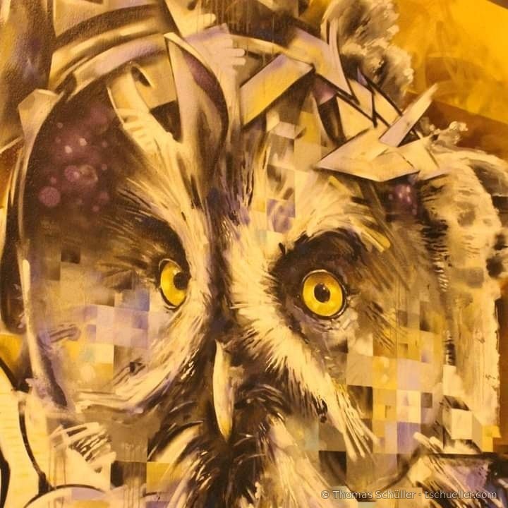Wandbild einer Eule mit gelben Augen, in Pixel und Splitter zerlegt