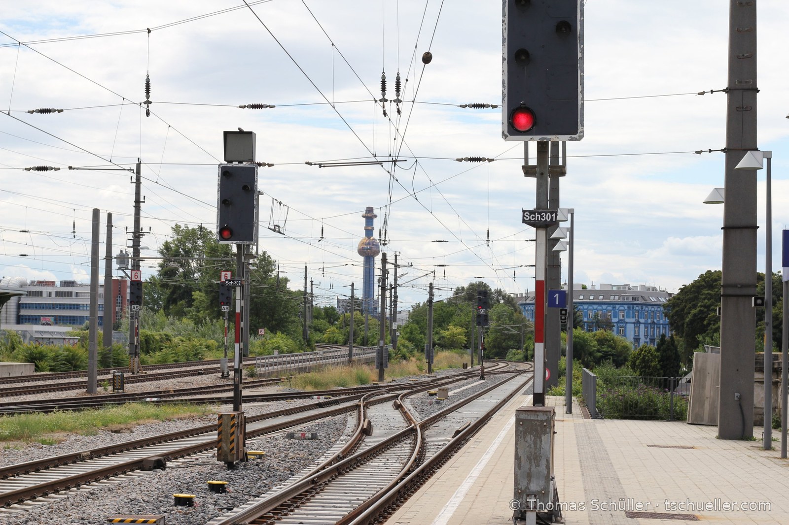Bahnsteigende mit Lichtsignalen und Oberleitung, hinten der Turm der Müllverbrennung Spittelau